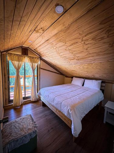 a bed in a room with a wooden ceiling at Cabaña Santa Amelia Antuco Pet Friendly in Peluca