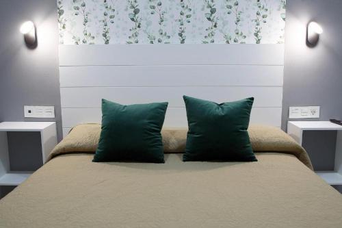a bedroom with a bed with two green pillows at Apartamentos Las trece llaves in Mérida