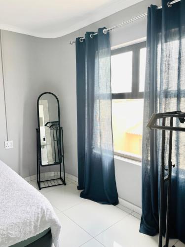 Pluto Guesthouse في والفيز باي: غرفة نوم بها ستائر زرقاء ومرآة