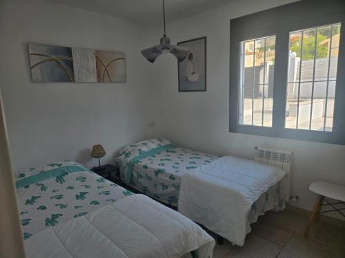 a bedroom with two beds and two windows at Villa Good Vibes in Ifach