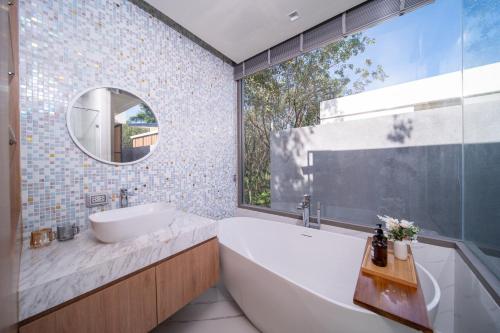 a bathroom with a tub and a sink and a mirror at 竹光别院 Bamboo Radiance Villa in Ban Thalat Choeng Thale
