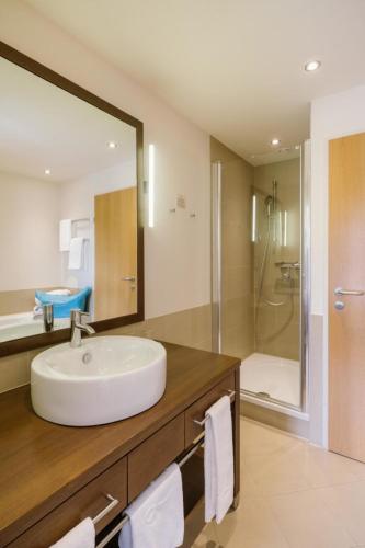 a bathroom with a white sink and a shower at Hotel & Spa Larimar in Stegersbach