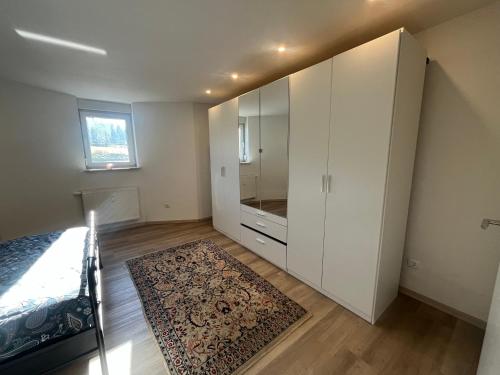 a bedroom with a white cabinet and a rug at Waldsee in Hilgert