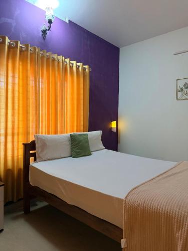 a bedroom with a bed with an orange and purple wall at Sea lumina in Varkala