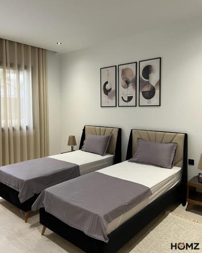 two beds sitting next to each other in a bedroom at Homz Maison in Sukrah