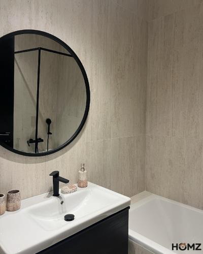 a bathroom with a sink and a mirror and a tub at Homz Maison in Sukrah