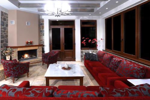 a living room with a red couch and a fireplace at Artemis Traditional Guesthouse in Levidhion
