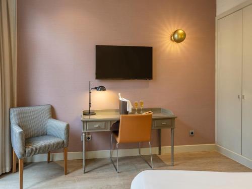 a room with a desk and a television on a wall at Regente Hotel in Madrid