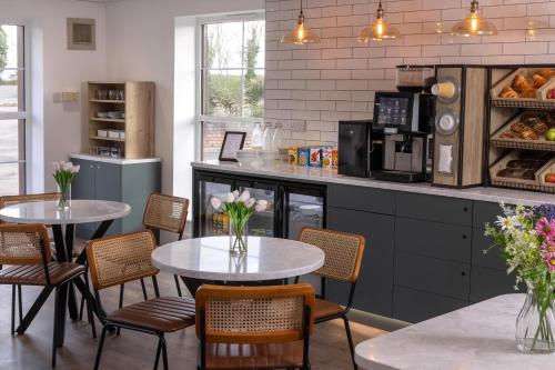 a kitchen with two tables and chairs and a counter at Best Western Leicester Oadby in Great Glen