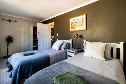 a bedroom with two beds and a fan at Dorpsig Cottage in Paarl