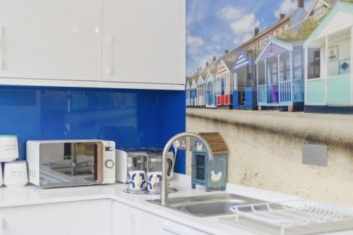 a kitchen counter with a sink with a toaster at Shiny Pebble in Southwold