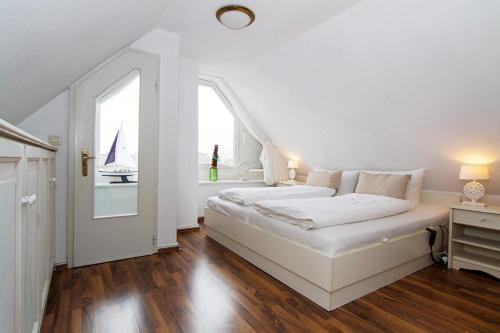 ein weißes Schlafzimmer mit einem Bett und einem Fenster in der Unterkunft Haus Seemöwe in Archsum