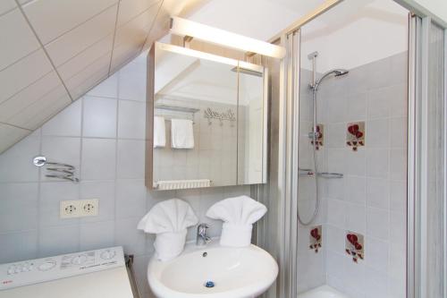 ein weißes Badezimmer mit Waschbecken und Dusche in der Unterkunft Haus Seemöwe in Archsum