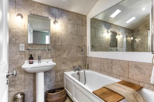 a bathroom with a tub sink and a mirror at The Cottage in Steeple Bumpstead