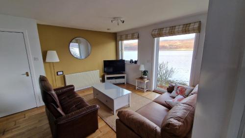 a living room with a couch and chairs and a television at Sea Drift Self Catering in Dunan