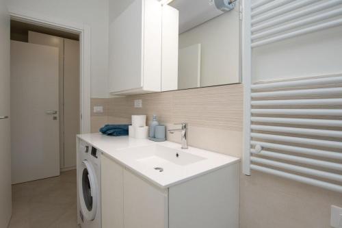 a white bathroom with a washing machine and a sink at Finalpia suite con box auto e deposito bici in Finale Ligure
