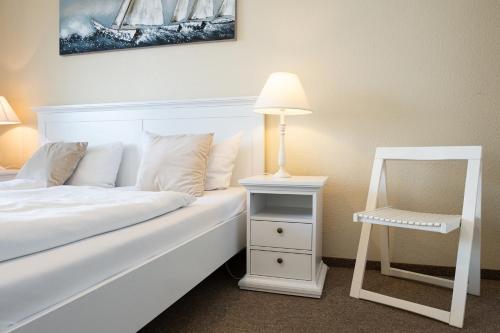 a bedroom with a white bed with a lamp and a chair at Norderhoog-Whg-45-2-OG-O-Wohnung-45 in Westerland