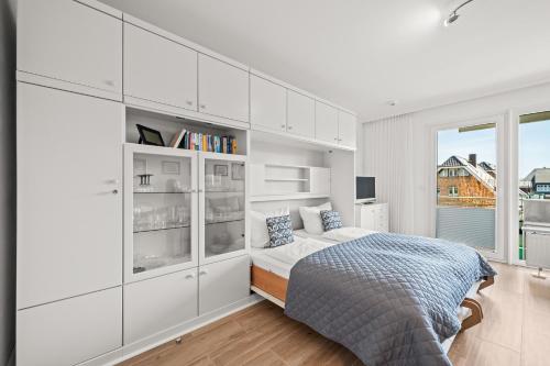 a white bedroom with a bed and a window at Norderhoog-Whg-33-1-OG-O-Wohnung-33 in Westerland