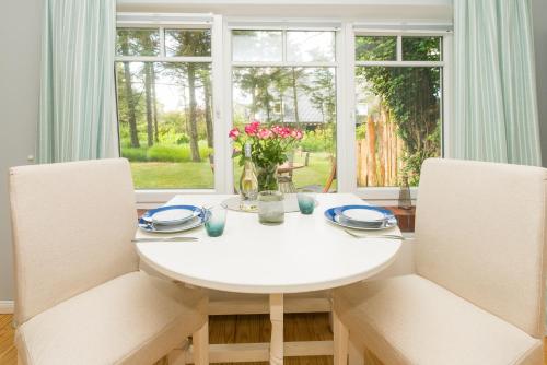 a white dining room table with two chairs and a window at Bandomir-Bungalow-Wohnung-02 in Westerland
