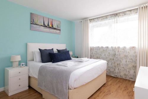 a bedroom with a bed with blue walls and a window at Sunny & Modern Near the Beach & Village w Parking in East Wittering
