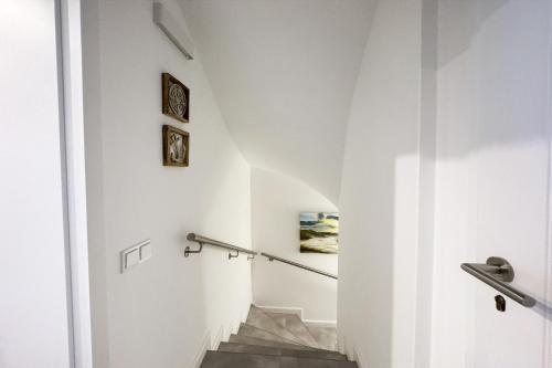 a hallway with white walls and stairs with a stair railing at Haus-Excelsior-Wohnung-08 in Rantum