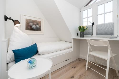 a white living room with a white couch and a table at Haus-Friesenperle in Westerland