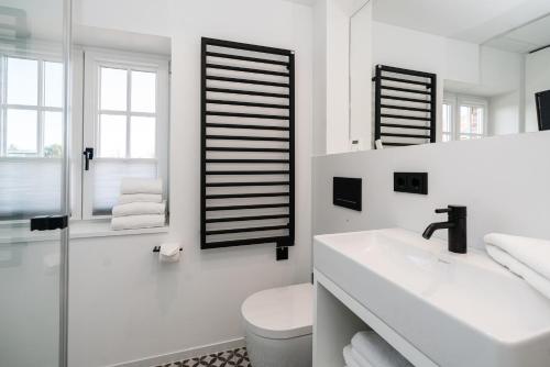 a white bathroom with a toilet and a sink at Haus-Friesenperle in Westerland