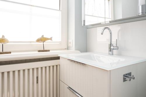 a white kitchen with a sink and a window at Tunghoern-Hues in Keitum