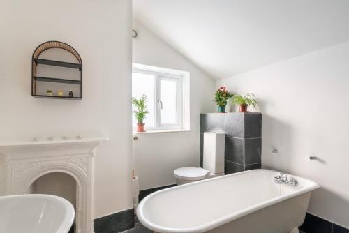 a white bathroom with a white tub and a fireplace at Arty House with Garden in Central Bristol in Bristol