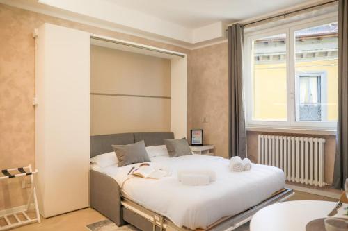 a bedroom with a large white bed and a window at BLUE WAVE by Design Studio in Bellano