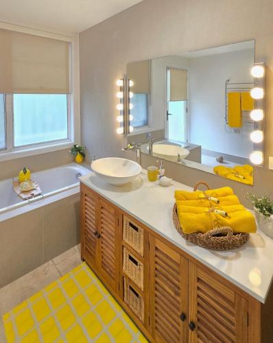 a bathroom with a sink and a tub and a mirror at The Hideaway Boutique Guest House in Jindalee