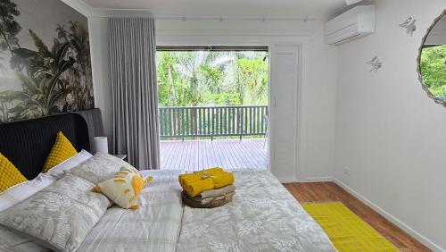 a bedroom with a bed with yellow pillows at The Hideaway Boutique Guest House in Jindalee