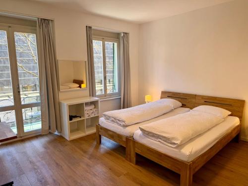 a bedroom with two beds and a large window at Downtown Apartments in Interlaken