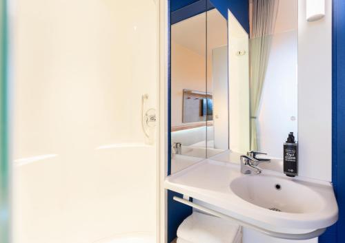 a white bathroom with a sink and a mirror at ibis budget Genève Aéroport in Geneva