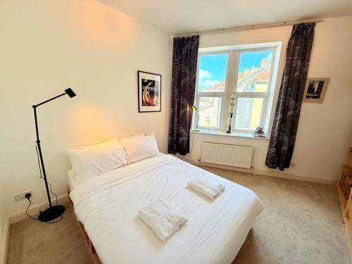 a white bed in a room with a large window at Perfect City Flat for Leisure & Work stays in Bristol