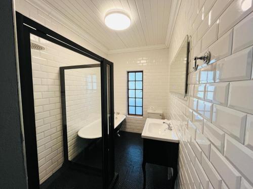 a white bathroom with two sinks and a mirror at Halfway House Hotel in Kimberley