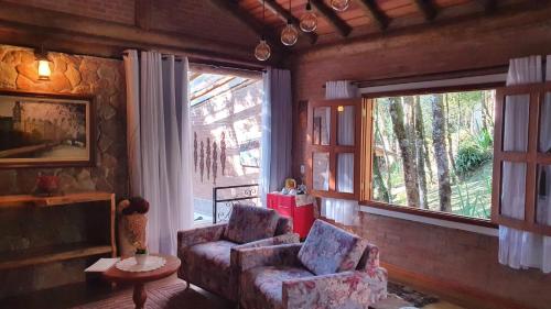 a living room with a couch and a chair and a window at Pousada Alto da Neblina in Monte Verde