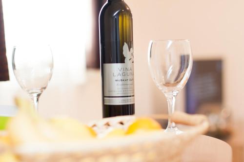 a bottle of wine and two glasses on a table at Rooms Garden Zagreb Airport in Velika Gorica