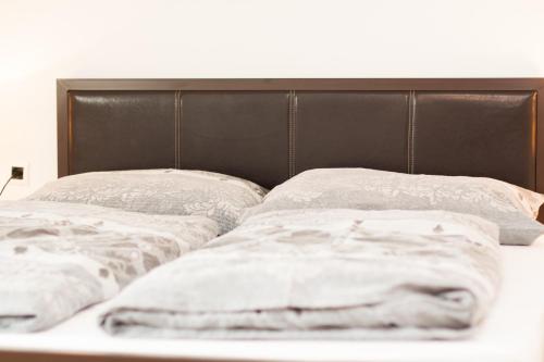 a bed with a black headboard and two pillows at Rooms Garden Zagreb Airport in Velika Gorica