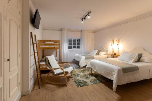 a bedroom with two beds and a chair in it at O VIOLAS - Art Coffee & Guesthouse in Praia de Mira