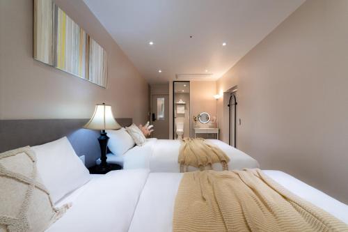 a bedroom with two white beds and a lamp at 4rest Stay Euljiro in Seoul