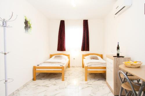 two beds in a room with a table and chairs at Rooms Garden Zagreb Airport in Velika Gorica