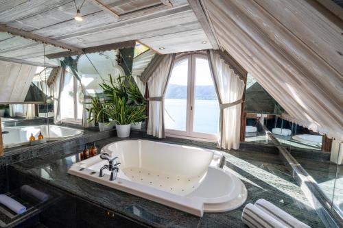 a bathroom with a large tub and a window at Hôtel La Maison Bleue par Yoann CONTE in Veyrier-du-Lac