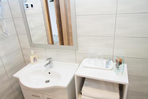 a white bathroom with a sink and a mirror at Rooms Garden Zagreb Airport in Velika Gorica