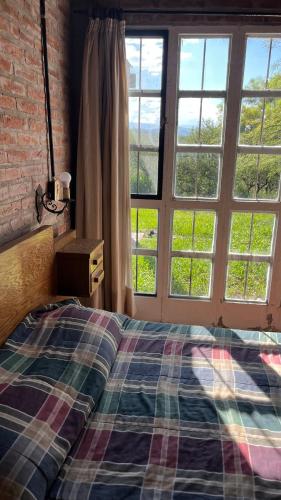 a bedroom with a bed and a large window at El Campito in Villa Icho Cruz