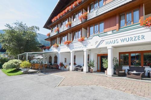 a hotel building with a courtyard with tables and chairs at Alpenhotel Wurzer in Filzmoos