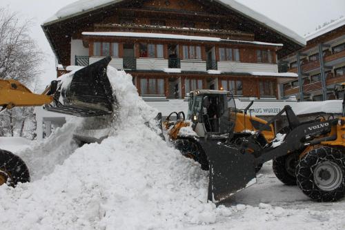 a bulldozer clearing a pile of snow in front of a house at Alpenhotel Wurzer in Filzmoos