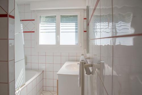 a white bathroom with a sink and a window at La villa Du Port in Veyrier-du-Lac