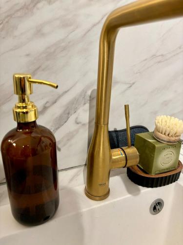 a bathroom sink with a bottle of soap and a faucet at La Scène Audomaroise - Appartement hyper centre in Saint-Omer