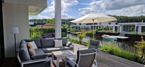 a patio with a couch and an umbrella and a house at Harderwold Villa - 384 in Zeewolde
